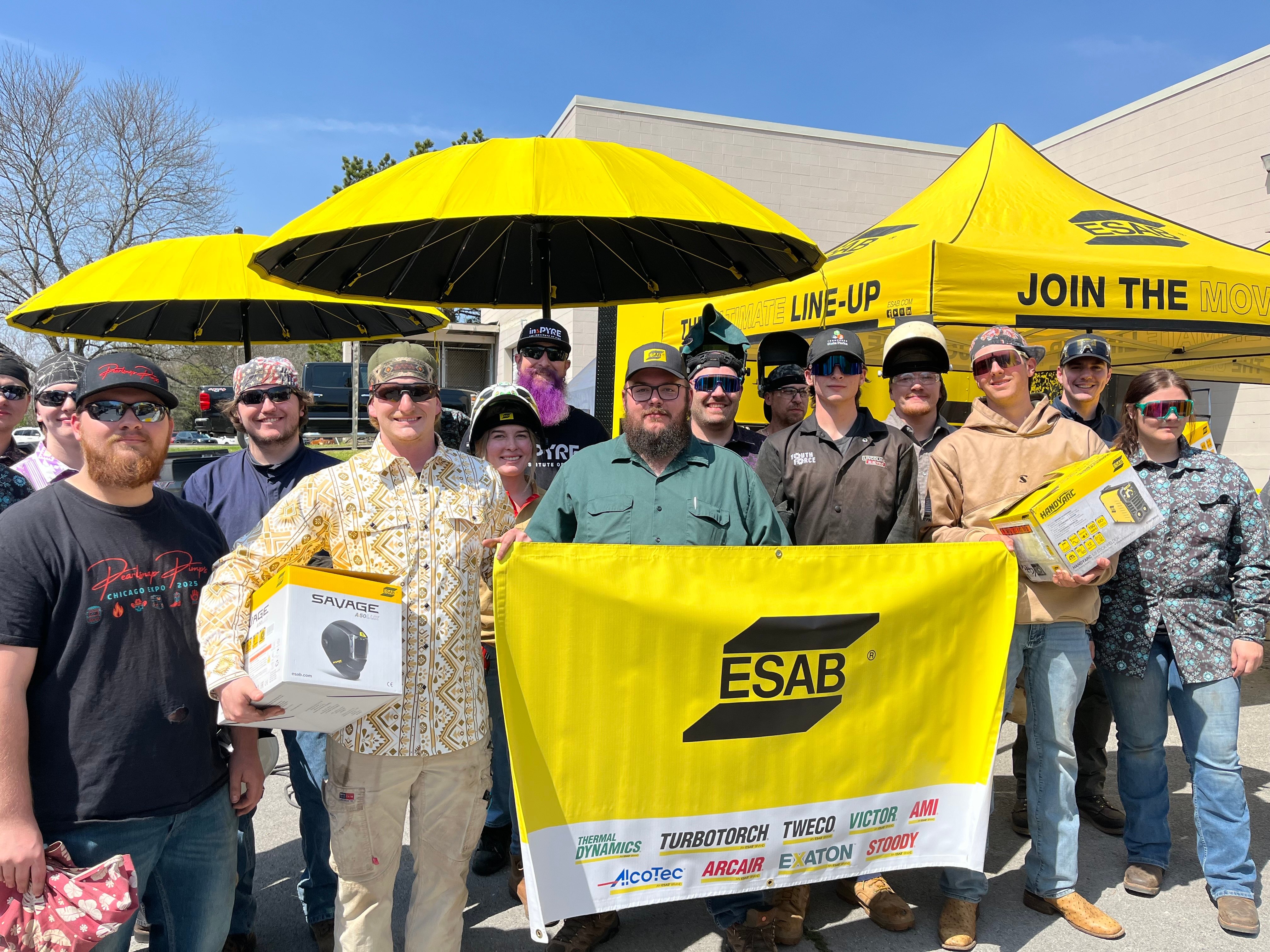 Welders in action at the ESAB Demo Tour, showcasing live welding demos under a bright yellow tent, focused on precision.